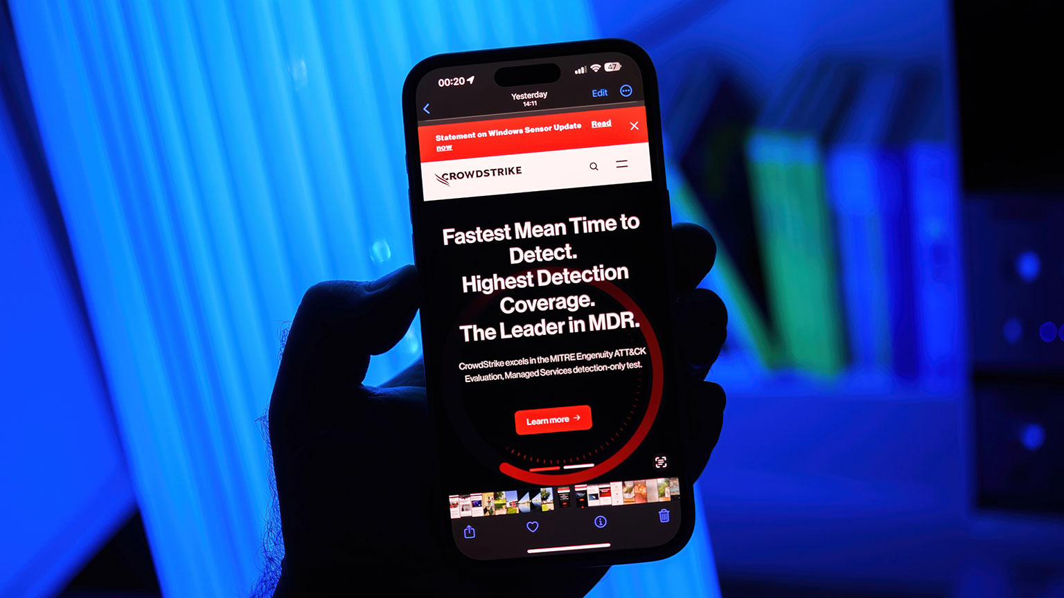 hand holding mobile phone displaying CrowdStrike advertisement